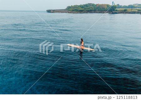 Woman waiting waves on surfboard in ocean. Drone view of woman during surfing Woman waiting waves on surfboard in ocean. Drone view of woman during surfing 125118813