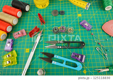 A set of sewing accessories laid out on a green mat. A set of sewing accessories laid out on a green mat. 125118830