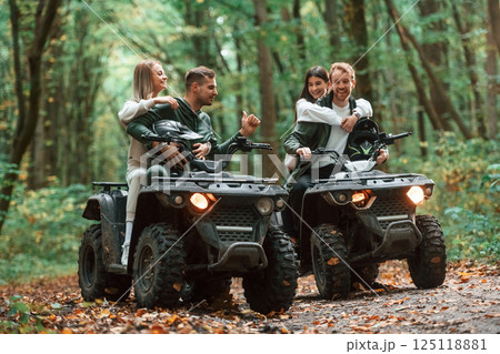 Smiling and having fun. Two couples on a quad bike in the forest during the day 125118881