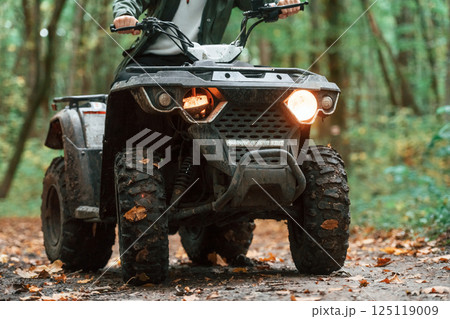Front view. ATV driver is in the forest, having a ride at daytime Front view. ATV driver is in the forest, having a ride at daytime 125119009