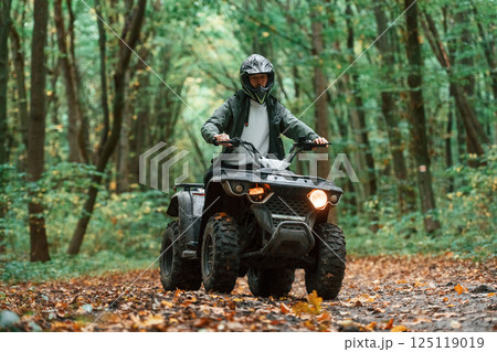 ATV driver is in the forest, having a ride at daytime 125119019