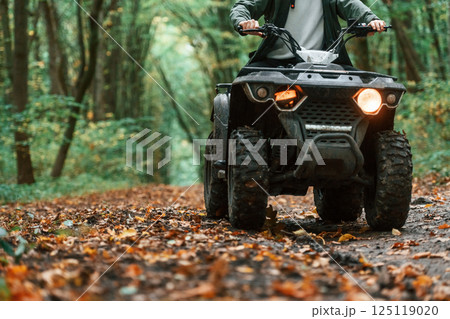 Close up view. ATV driver is in the forest, having a ride at daytime 125119020