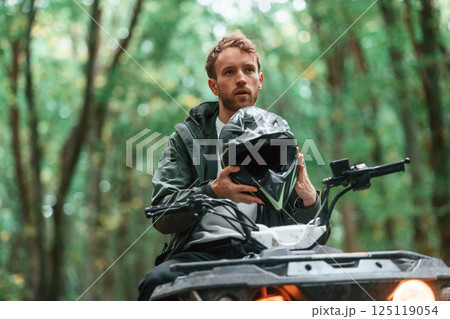 With safety helmet. TV driver is in the forest, having a ride at daytime With safety helmet. TV driver is in the forest, having a ride at daytime 125119054