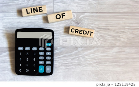 there is a calculator and wooden blocks with the inscription "CREDIT LINE". Workplace close-up. there is a calculator and wooden blocks with the inscription "CREDIT LINE". Workplace close-up. 125119428