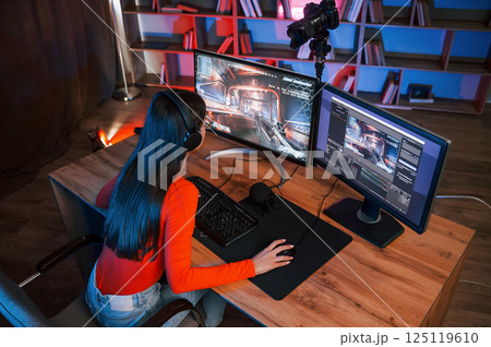 Focused on the game process. Young beautiful streamer is indoors with pc 125119610