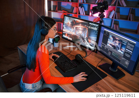 Focused on the game process. Young beautiful streamer is indoors with pc 125119611