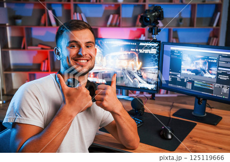 Male game streamer in casual clothes is indoors with pc 125119666