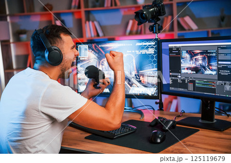 Male game streamer in casual clothes is indoors with pc 125119679