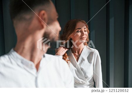 Man looking at his woman. Beautiful young couple is standing together against dark green background Man looking at his woman. Beautiful young couple is standing together against dark green background 125120032