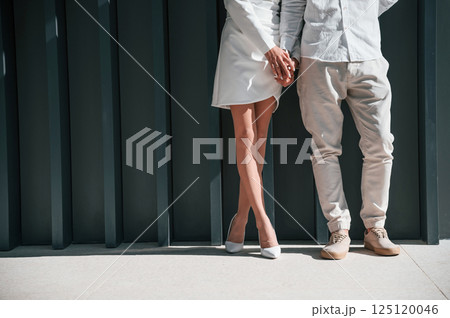 Close up view. Beautiful young couple is standing together against dark green background Close up view. Beautiful young couple is standing together against dark green background 125120046