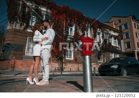 Embracing each other. Beautiful young couple is together on the street against old building Embracing each other. Beautiful young couple is together on the street against old building 125120052