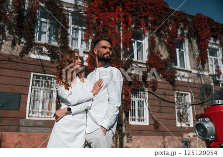 Embracing each other. Beautiful young couple is together on the street against old building 125120054
