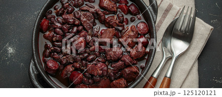 Brazilian feijoada with black beans, sausage and meat in a pot, top view 125120121