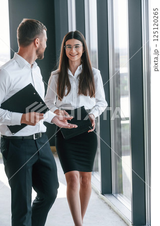 Holding tablet. Man and woman in formal clothes are working together indoors 125120265