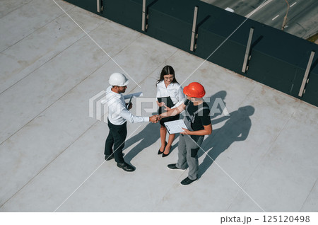 Doing handshake. Top view of men and woman that are on construction site, working together on the project 125120498