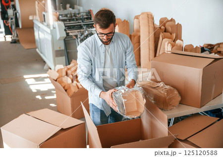 Packaging the wooden sheets. Print house worker in white clothes is indoors 125120588