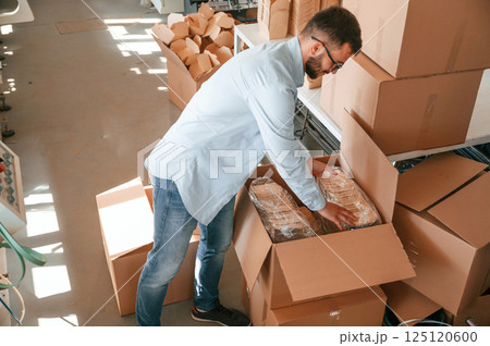Packaging the wooden sheets. Print house worker in white clothes is indoors 125120600