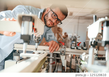 Using the cutting machine. Print house worker in white clothes is indoors Using the cutting machine. Print house worker in white clothes is indoors 125120610