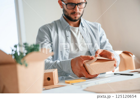 Process of making beautiful little wooden box. Print house worker in white clothes is indoors 125120654