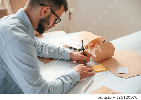 Drawing process. Print house worker in white clothes is indoors 125120670