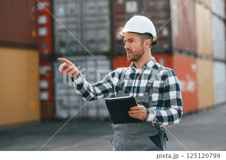 Giving instructions by the hand. Male worker is on the location with containers 125120799