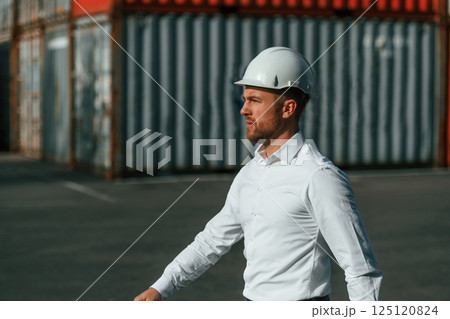 Walking, side view. Male worker is on the location with containers Walking, side view. Male worker is on the location with containers 125120824