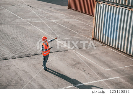 Conception of business. Walking with tablet. Male worker is on the location with containers 125120852