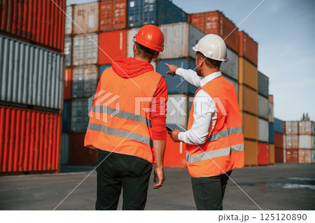 Showing the objects. Two male workers is on the location with containers Showing the objects. Two male workers is on the location with containers 125120890