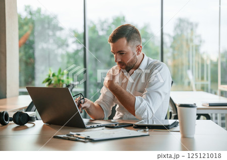 Thoughtful look. Man in formal clothes is working in the modern office Thoughtful look. Man in formal clothes is working in the modern office 125121018