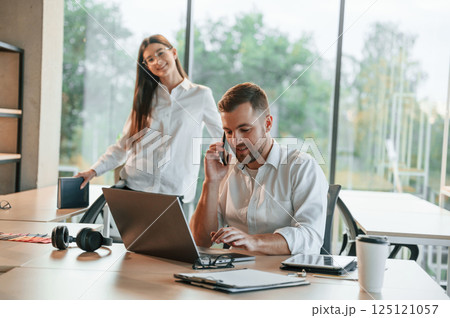 Boss is talking by phone. Man and woman are working in the modern office together Boss is talking by phone. Man and woman are working in the modern office together 125121057