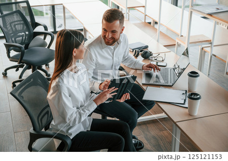 With graphic tablet and laptop. Man and woman are working in the modern office together With graphic tablet and laptop. Man and woman are working in the modern office together 125121153