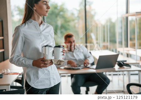 Giving drink to the boss. Man and woman are working in the modern office together Giving drink to the boss. Man and woman are working in the modern office together 125121179