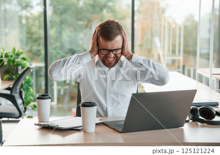 Angry, feeling tired and bad. Man in formal clothes is working in the modern office 125121224