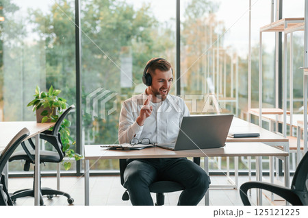 Using laptop. Man in formal clothes is working in the modern office Using laptop. Man in formal clothes is working in the modern office 125121225
