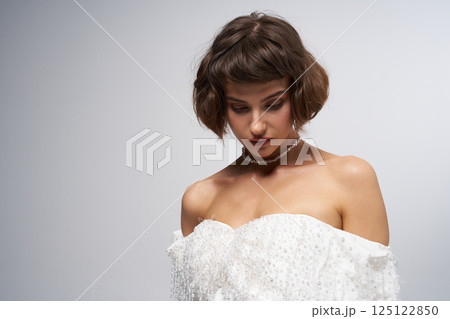 Elegant model showcases stunning white gown in a minimalist studio setting during a fashion event Elegant model showcases stunning white gown in a minimalist studio setting during a fashion event 125122850