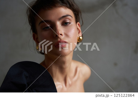 Model poses in minimalist setting with dramatic lighting and elegant accessories in a contemporary studio Model poses in minimalist setting with dramatic lighting and elegant accessories in a contemporary studio 125122864
