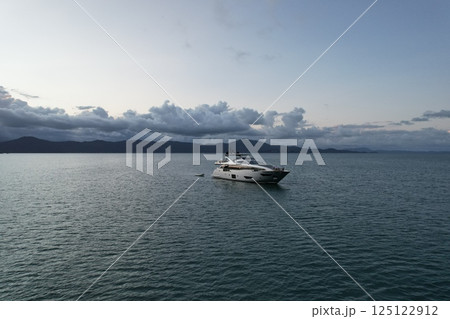 Elegant yacht sailing across calm waters at sunset near mountains Elegant yacht sailing across calm waters at sunset near mountains 125122912