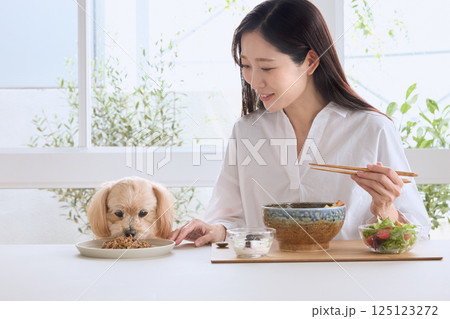 愛犬と一緒に食事を楽しむ女性 愛犬と一緒に食事を楽しむ女性 125123272