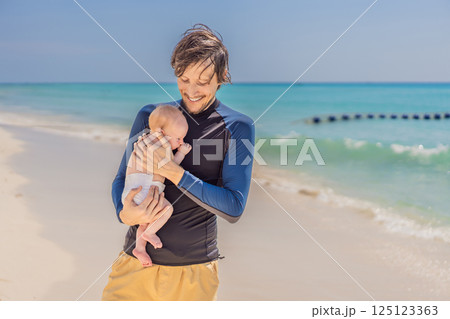 Father holding his newborn baby by the turquoise sea, enjoying a peaceful and loving moment. Family bonding, fatherhood, and travel with baby concept 125123363