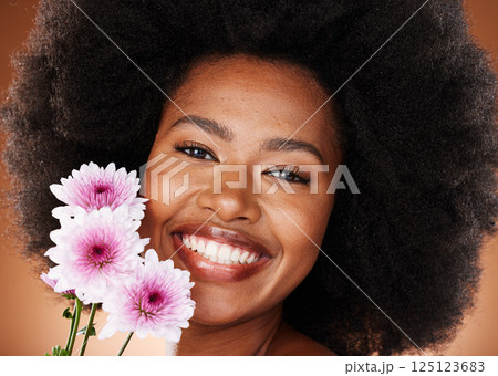 Black woman, face or afro hair with daisy flowers on studio background for gentle skincare, vibrant glow or organic dermatology. Zoom, portrait or happy smile beauty model with natural hair and plant 125123683
