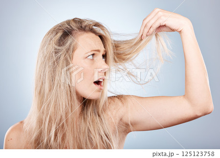 Woman, shocked and hair care health or cosmetics wellness for hair loss in studio. Young blonde model, dry and messy hairsyle or girl upset for split ends or damaged hair in grey background studio Woman, shocked and hair care health or cosmetics wellness for hair loss in studio. Young blonde model, dry and messy hairsyle or girl upset for split ends or damaged hair in grey background studio 125123758