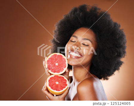 Black woman, afro hair or grapefruit for face skincare, healthcare wellness glow or vitamin c dermatology routine. Smile, happy or beauty model with natural hair, citrus food or vegan facial product Black woman, afro hair or grapefruit for face skincare, healthcare wellness glow or vitamin c dermatology routine. Smile, happy or beauty model with natural hair, citrus food or vegan facial product 125124005