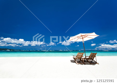 Sun umbrella and wooden beds on tropical beach. Caribbean vacation 125125591