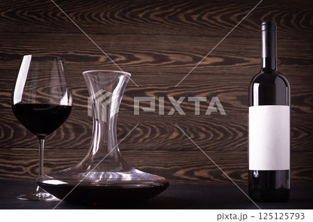 Decanter, glass and bottle with red wine on wooden rustic background Decanter, glass and bottle with red wine on wooden rustic background 125125793