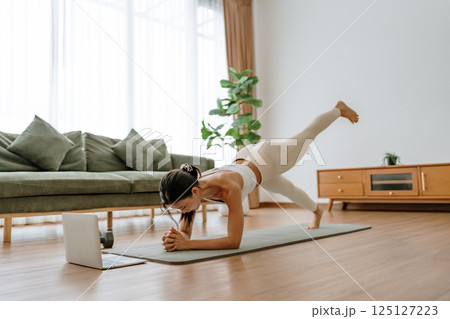 Young Asian woman in sportswear doing plank on training mat Young Asian woman in sportswear doing plank on training mat 125127223