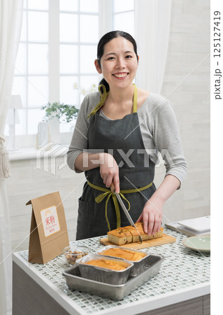 キッチンで米粉のパウンドケーキを作る女性 キッチンで米粉のパウンドケーキを作る女性 125127419