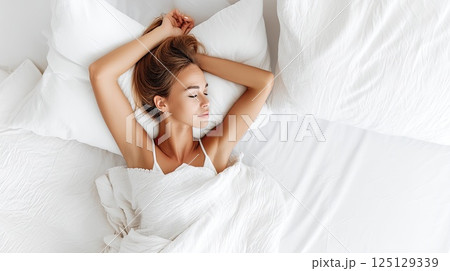 Close up of a Caucasian young woman sweet sleeping on white pillow. The young woman’s blissful sleep is highlighted by her gentle features on a white pillow. 125129339