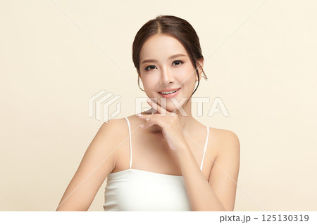 A beautiful young Asian woman with clean, fresh skin against a beige background. Skincare, facial treatment, cosmetology, beauty, and spa. An elegant portrait of an Asian woman. A beautiful young Asian woman with clean, fresh skin against a beige background. Skincare, facial treatment, cosmetology, beauty, and spa. An elegant portrait of an Asian woman. 125130319