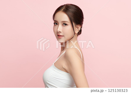 A beautiful young Asian woman with clean, fresh skin against a pink background. Skincare, facial treatment, cosmetology, beauty, and spa. An elegant portrait of an Asian woman. 125130323