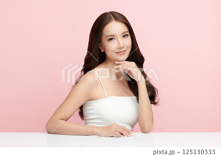 A beautiful young Asian woman with clean, fresh skin against a pink background. Skincare, facial treatment, cosmetology, beauty, and spa. An elegant portrait of an Asian woman. A beautiful young Asian woman with clean, fresh skin against a pink background. Skincare, facial treatment, cosmetology, beauty, and spa. An elegant portrait of an Asian woman. 125130333